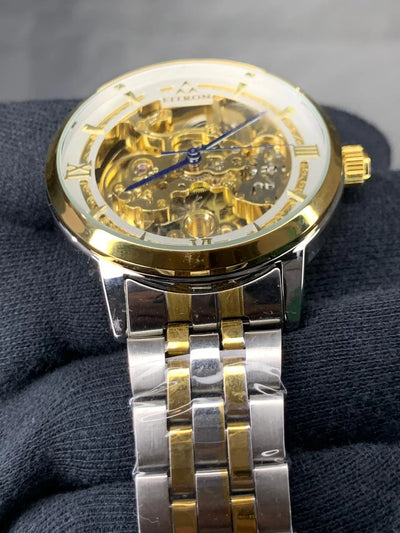Gold and silver watch with a detailed mechanism on a dark background