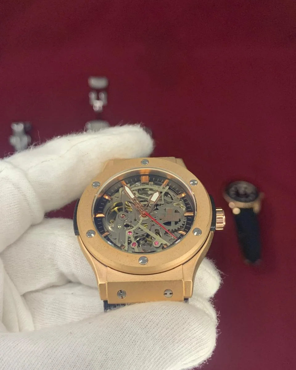 Gold wristwatch with intricate design held by a gloved hand on a red background