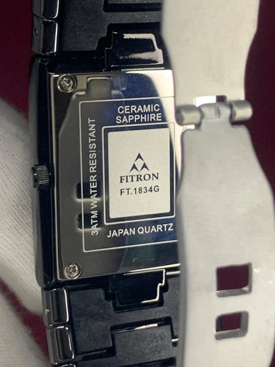 Close-up of a Fitron watch with brand details on a white background