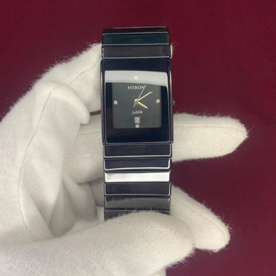 Watch held by a gloved hand on a red background