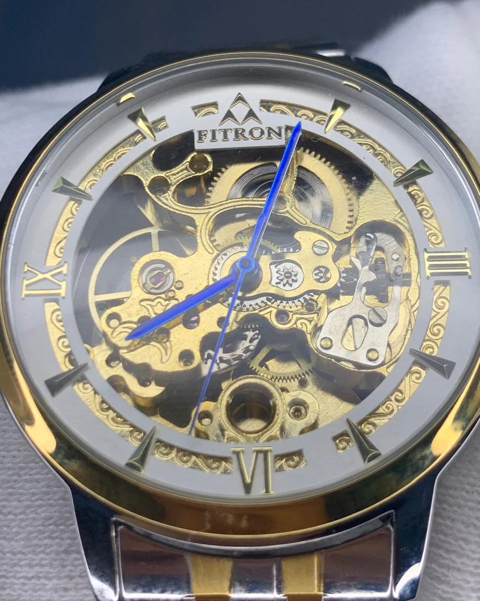 Gold and silver watch with visible mechanism on a gray background