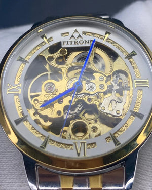 Gold and silver watch with visible mechanism on a gray background