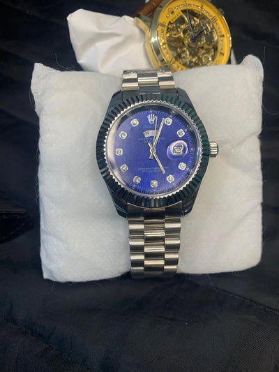 Luxury watch with blue face and silver case on a white cushion
