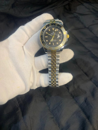 Luxury watch with a gold and silver band on a dark textured surface