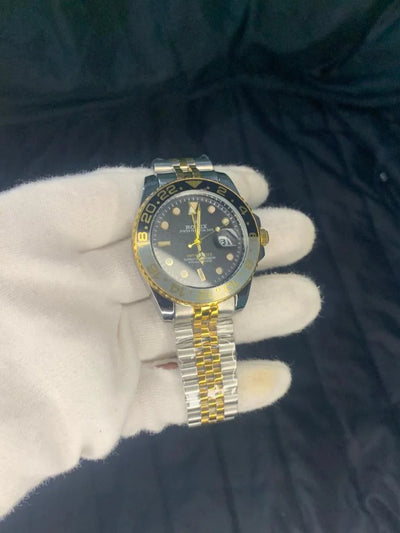 Gold and silver watch on a dark surface with a white glove