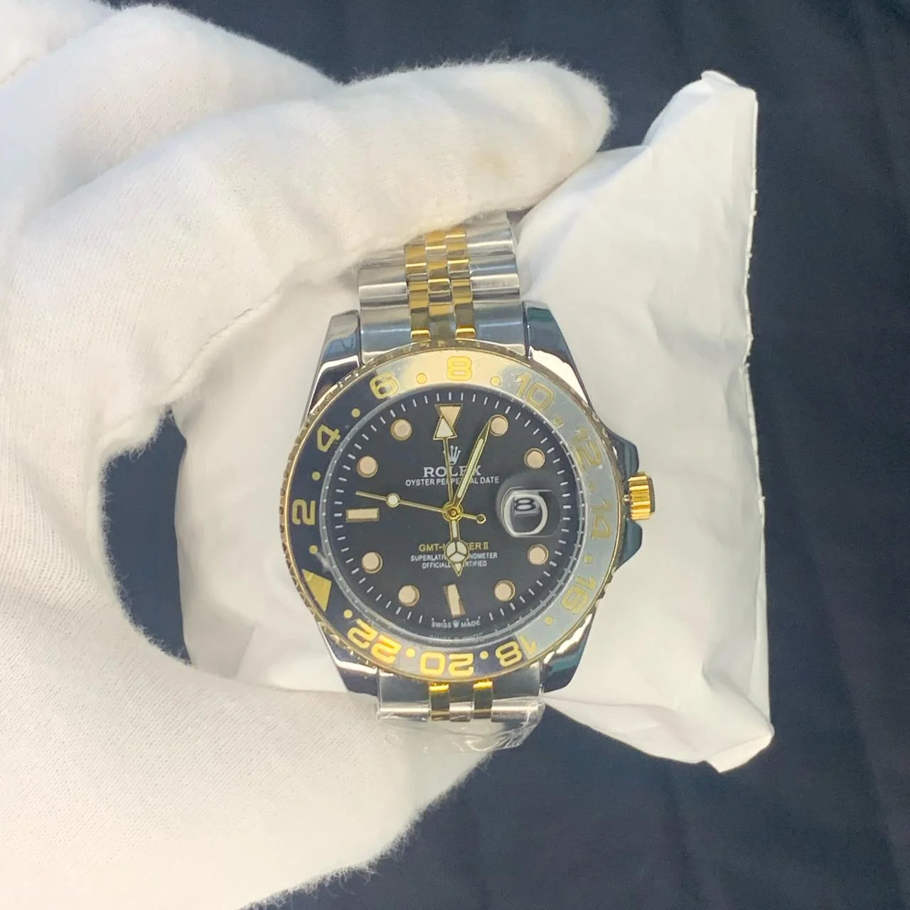 Rolex watch with black dial and gold accents on a white cushion
