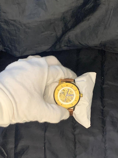 Gold watch on a white cloth with a dark background