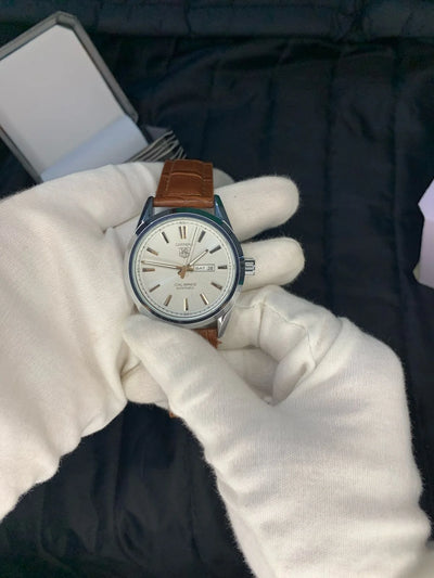 Watch held by a gloved hand with a dark background