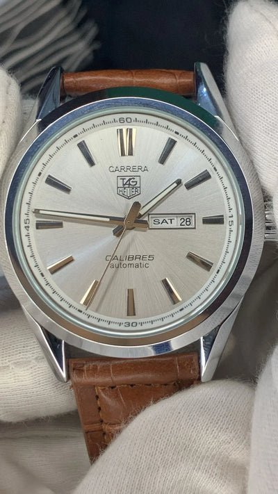 Watch with brown leather strap and silver dial on a white background