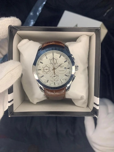 Watch with brown leather strap and white face in a clear box